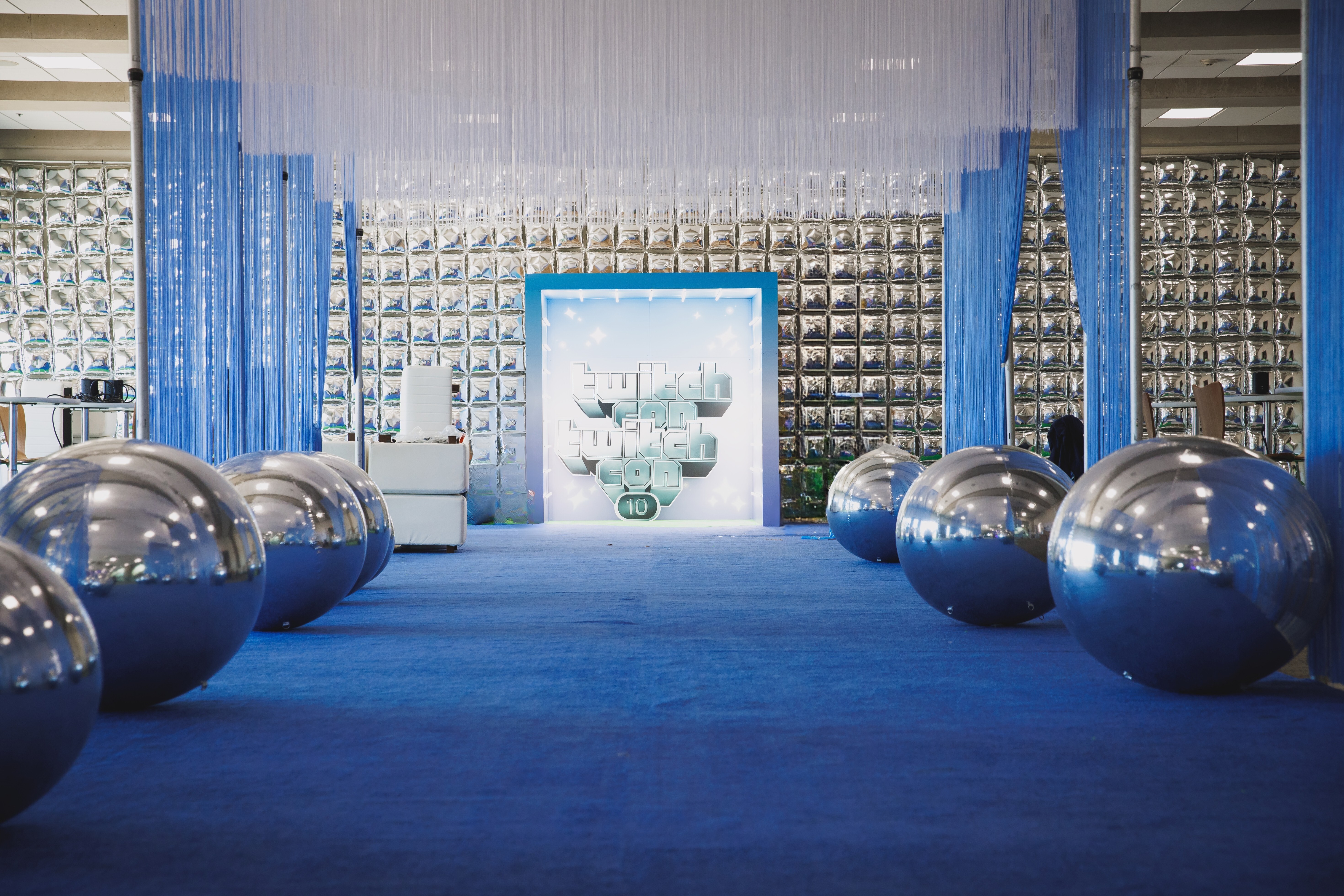 Custom blue and white string curtain installation with hanging panels and reflective spheres at a corporate event.